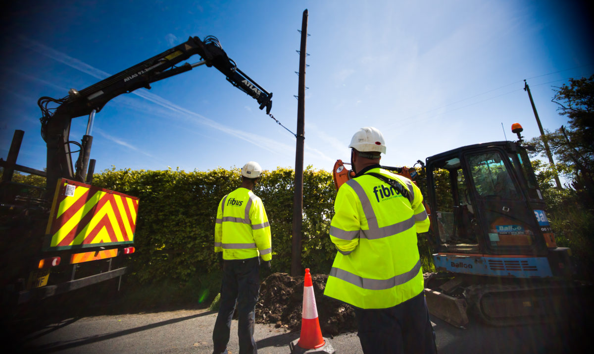 workers with heavylifting equipment install fibre cables